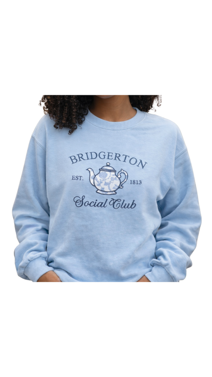 African American woman wearing Tea Time Bridgerton inspired bookish embroidered sweatshirt in bookstore, cozy romance reader outfit